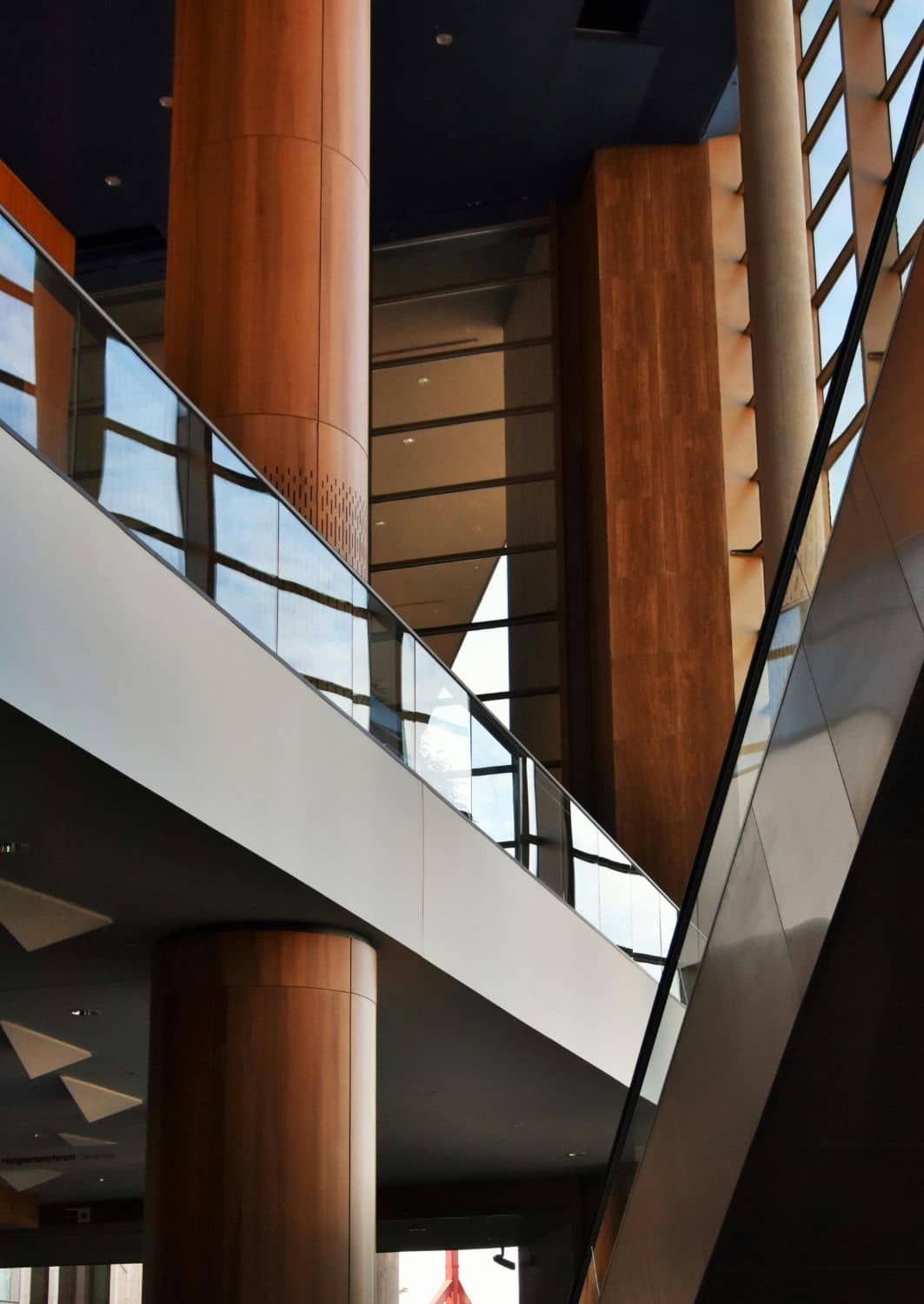 Timber and glass atrium with escalators inside a modern commercial building