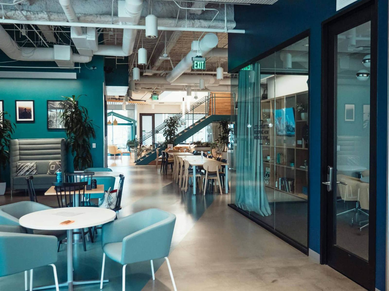 Bright open-plan office with glazed meeting rooms and an illuminated exit sign