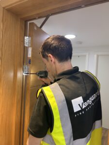 Vanguard engineer fitting new hinges to a flat entrance fire door