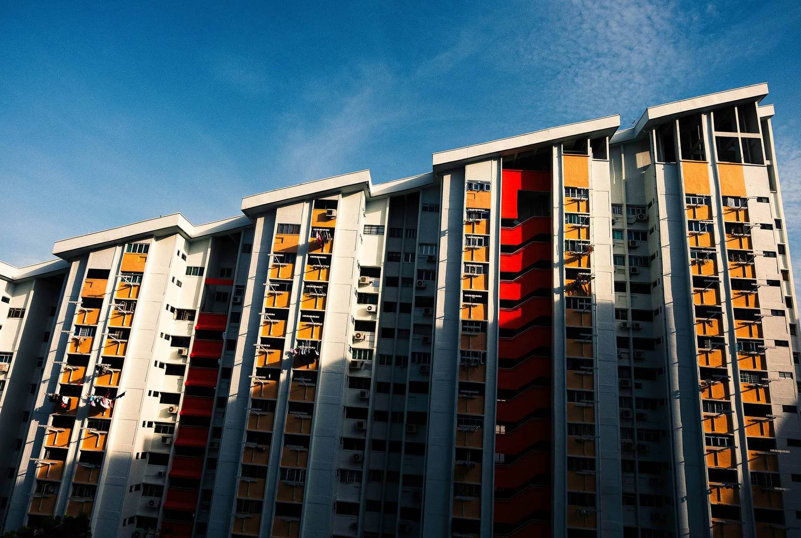 Residential tower block with orange balconies against a blue sky
