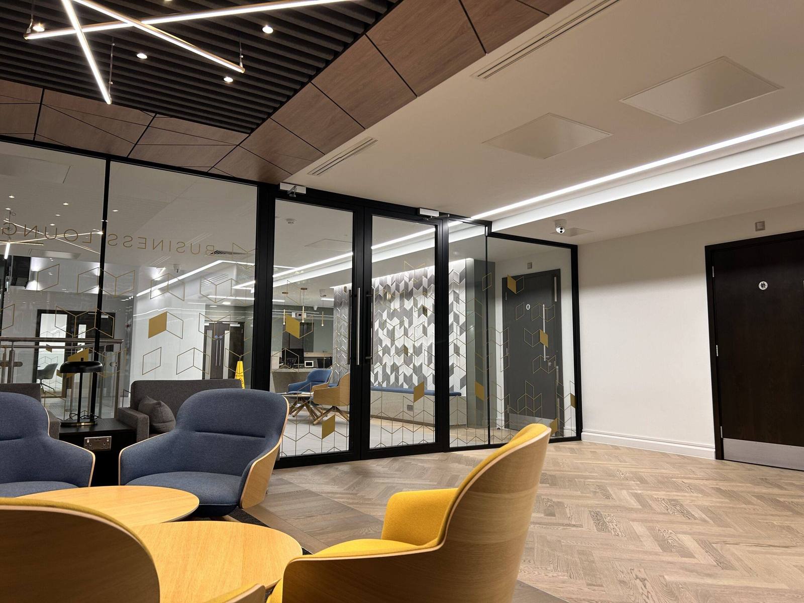 Modern office corridor with glazed partitions and a dark fire door