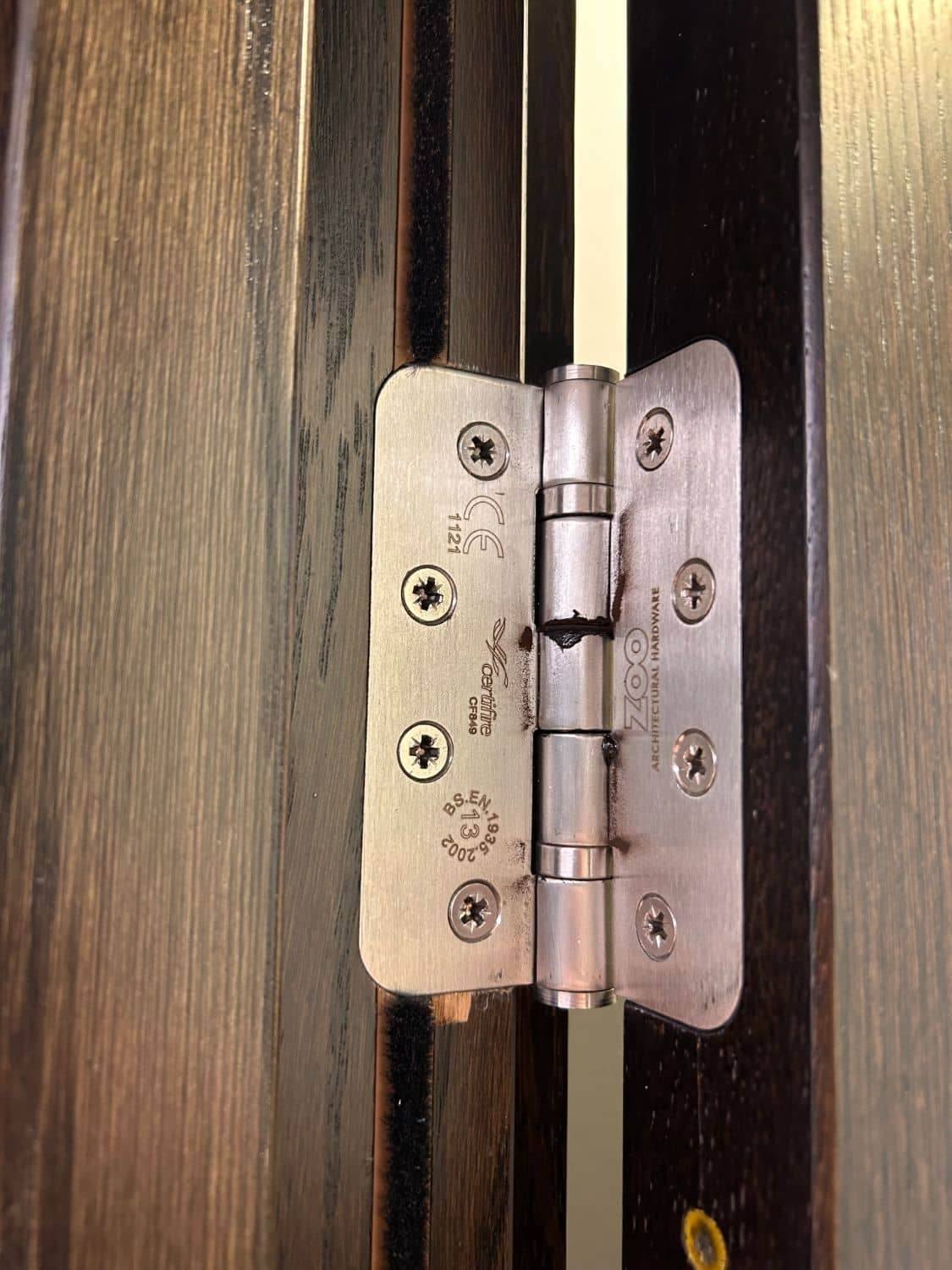 Close-up of a CE-marked fire-rated hinge fitted to a timber fire door