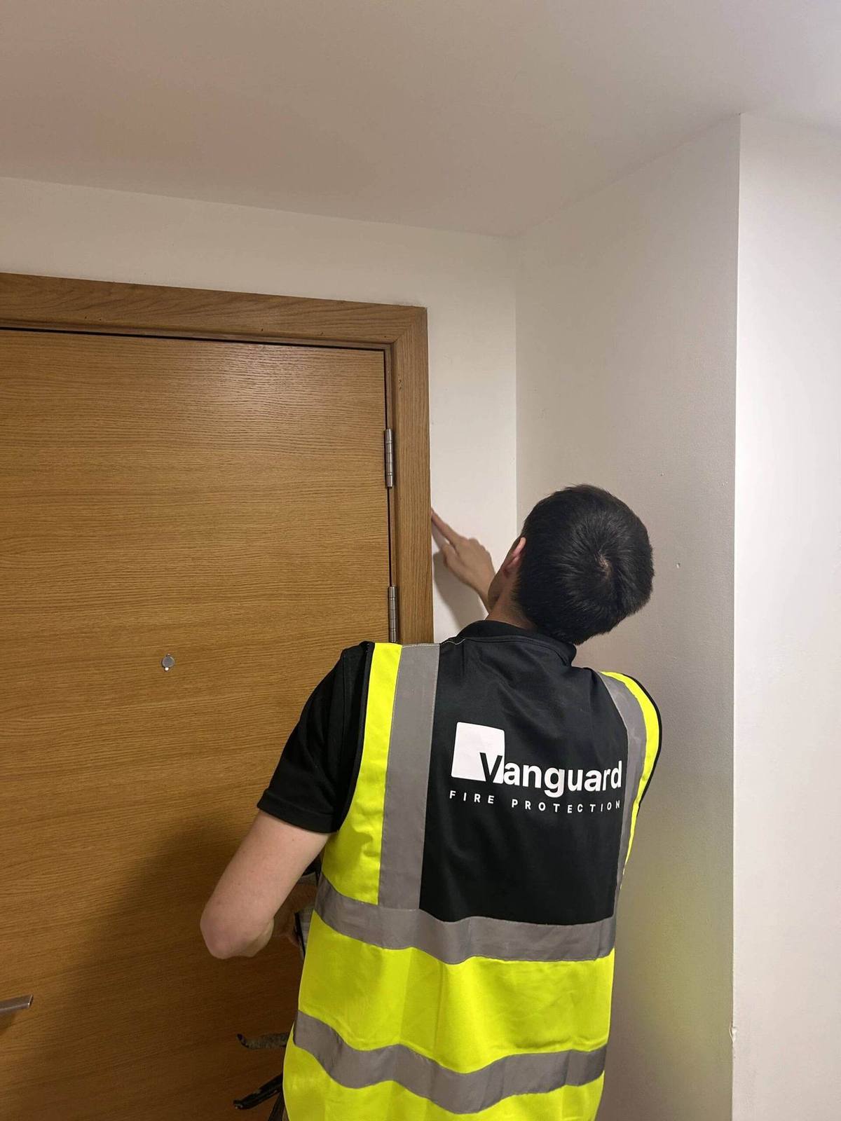 Vanguard engineer inspecting the hinges of a timber fire door
